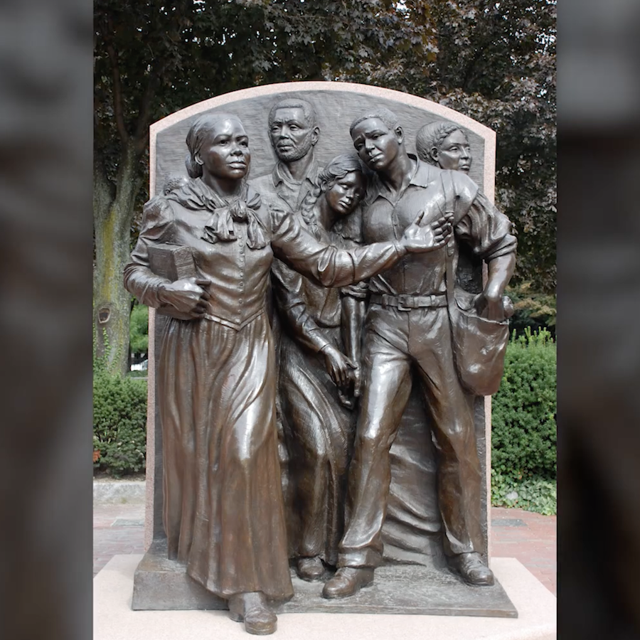 Photo of a memorial by Fern Cunningham titled “Step on Board.” The memorial depicts Harriet Tubman holding a Bible and guiding four other people. It is located in Boston and was dedicated in 1999.